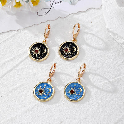 Blue and black enamel sun moon star disc leverback earring pairs on white stone