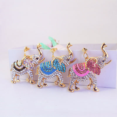 Three jeweled elephants in black, blue and pink stand side by side.