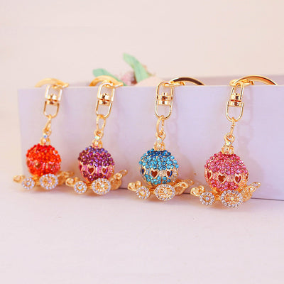 Four pumpkin carriage keychains in orange, purple, blue, and pink arranged side by side.