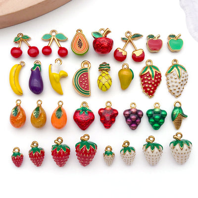 Metallic strawberry and cherry charms arranged on a light background