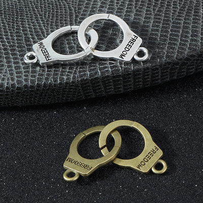 Antique silver and antique brass handcuff connector charms stamped FREEDOM stacked together