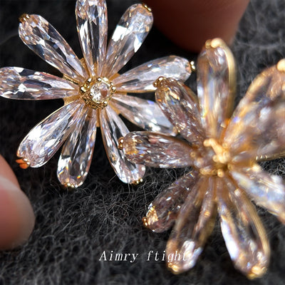 Gold large clear marquise daisy studs held close on dark fabric