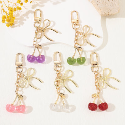Group of five cherry keychains in red, pink, clear, purple and green with gold bows
