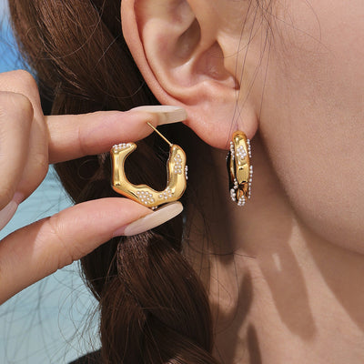 Gold irregular C-hoop with shell beads worn and held by model