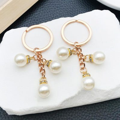 Front product photo of ivory faux pearl and rhinestone charm keychain with gold tone ring showing the pictured design ar