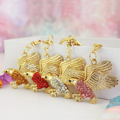 A row of gold-tone eagle charms displays amber, red, clear, and pink rhinestone bodies.
