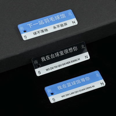 Three acrylic road sign charms in blue-and-white and black-and-white with Chinese text and pinyin lettering on a dark te