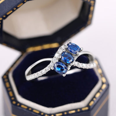 Product view showing silver-tone crisscross ring with three blue oval stones