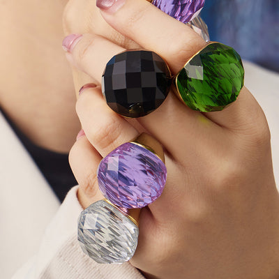 Styled hand view of oversized colored faceted glass stone rings in main image 1.