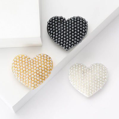 Gold Heart, White Heart, Black Heart brooch styles arranged on a light display