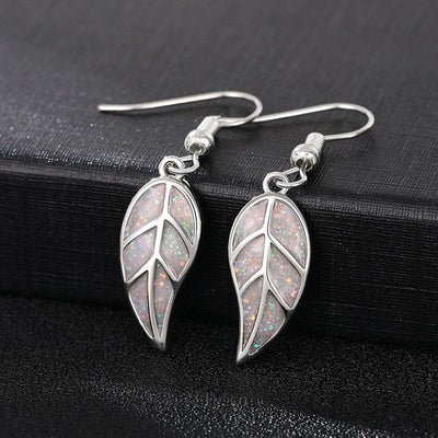 Pair silver opal glitter leaf hook earrings on black surface