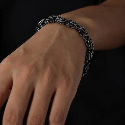 Two-tone black steel textured link bracelet worn on wrist dark background