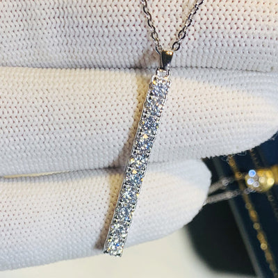 Silver clear crystal bar pendant held over white glove