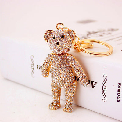 Angled front view of a clear rhinestone bear beside its gold-tone split key ring.