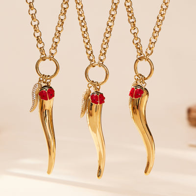Three gold chili pepper pendants with ladybug and wing charms on chains