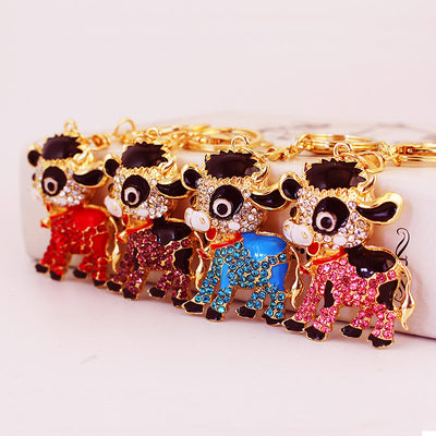 Four gold-tone cow keychains in red, purple, blue, and pink.