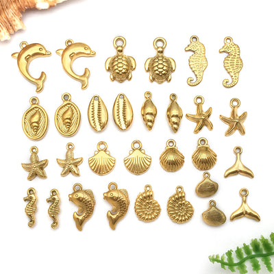 Gold-tone mermaid and turtle charms arranged on a light background