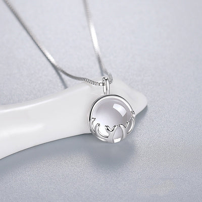 Silver round moonstone antler pendant on white ceramic rest gray surface