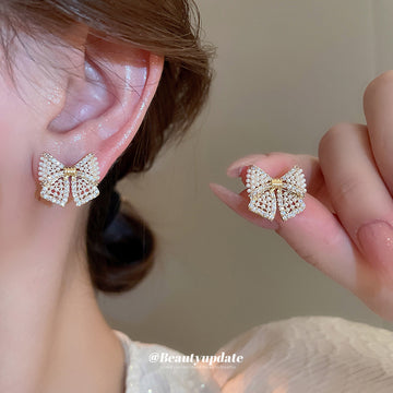 Gold Tone Crystal Bow Stud Earrings With Small Pearl Details