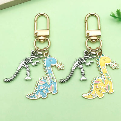Two floral long-neck dinosaur keychains in blue and yellow sit beside silver-tone skeleton charms.