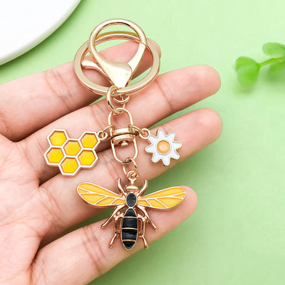 Image 1 showing a hand holding a keychain with two bees and honeys.