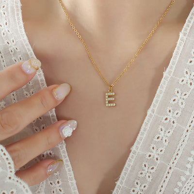 Model wearing gold E letter pendant necklace white lace top