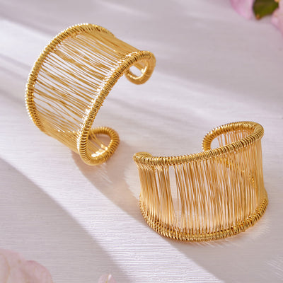 Two gold wire-wrapped open cuff bangles on white surface