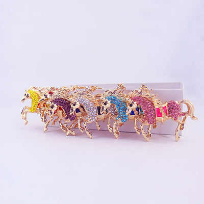 Six gold-tone horse charms with multicolored rhinestone details lined up together.