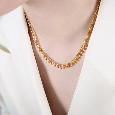 Gold curb necklace with pink enamel bead fringe worn on collarbone