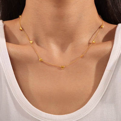 Model wearing gold multi-heart station necklace at collarbone