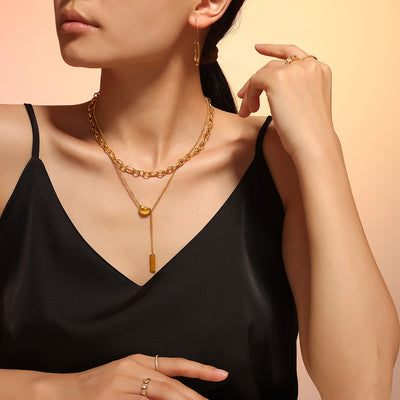 Model wearing gold layered chunky chain with bean pendant and bar drop