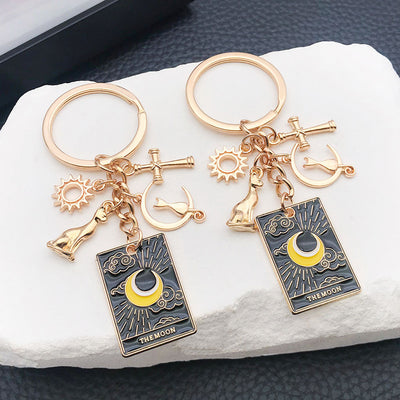 Front product photo of black celestial tarot cat and moon charm keychain pair with gold tone hardware showing the pictur
