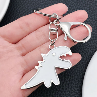 Front display of white and black Tyrannosaur enamel keychains with visible colors and attached hardware