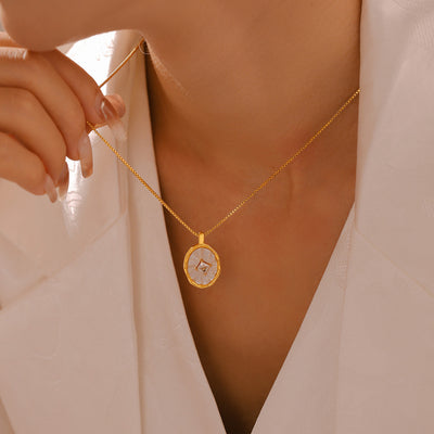 Model wearing gold oval shell zircon pendant necklace on white blouse