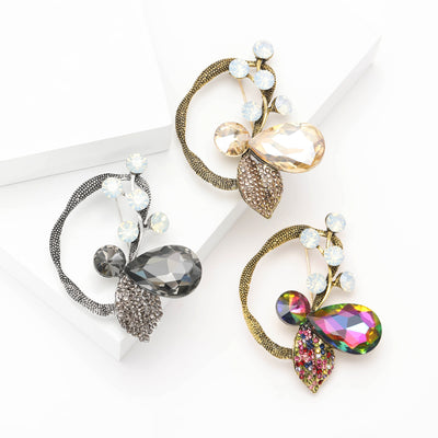 Front view of the faceted glass flower brooch with curved crystal stem on a white background