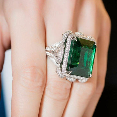 Oversized emerald-green rectangular cluster ring worn on a hand