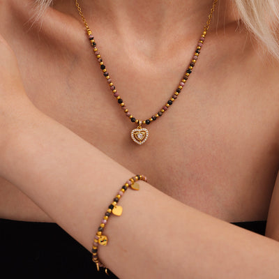 Model wears stone bead heart pendant necklace and heart bracelet