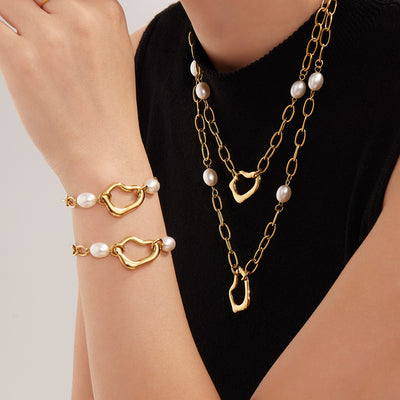 Model in black top wearing gold heart-link pearl necklaces and bracelets