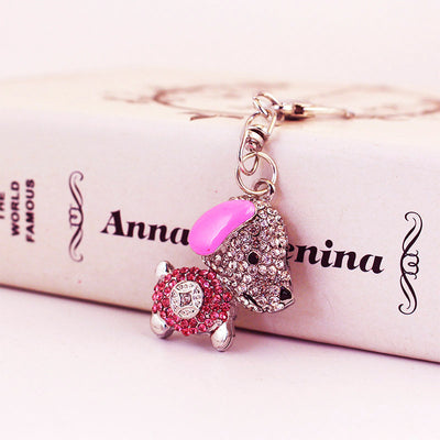 Pink dog charm with clear and pink rhinestones against a printed box.