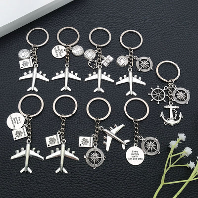 Front product photo of antique silver airplane globe passport travel keychain showing the pictured design arrangement