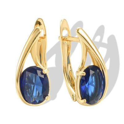 Pair of gold oval blue CZ hinged huggie hoop earrings on white