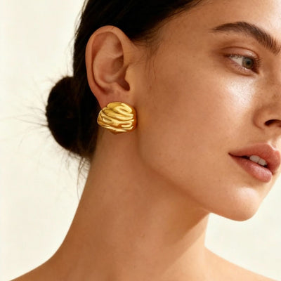 On-ear view of sculpted ripple stud earrings in main image 1.