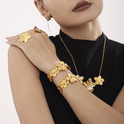 Model in black top wearing gold textured flower necklace cuff and rings