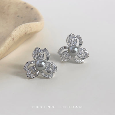 Silver flower studs with gray pearl centers on pale surface