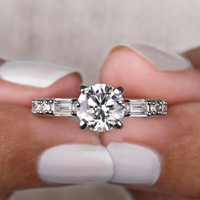 Silver round four-prong CZ ring front close-up held between fingers