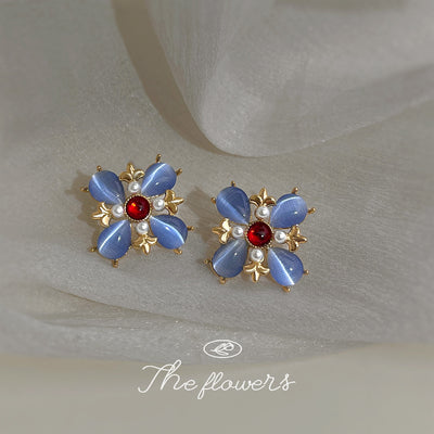 Gold-tone blue-petal red-center flower earrings in the first product display.
