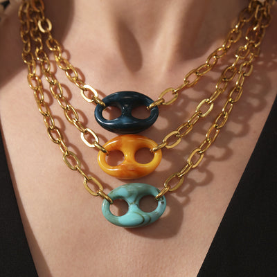 Layered gold chains with dark green yellow turquoise mariner pendants on neck