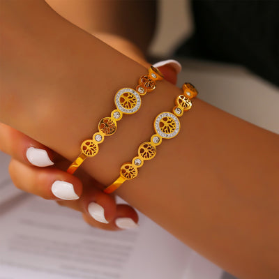 Two gold Tree of Life bangles worn stacked on wrist