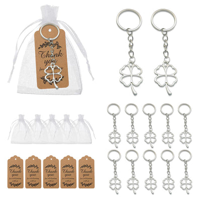 A white drawstring bag, brown thank-you tags, and multiple silver tone clover keychains are arranged on a white backgrou