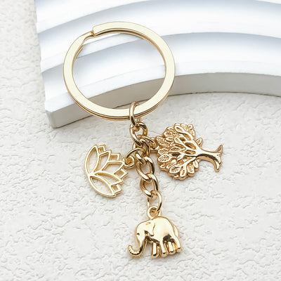 Front view of a gold-tone key ring with elephant, lotus, and leafy tree charms.